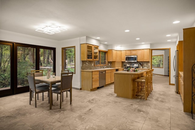 kitchen featuring a kitchen island, stainless steel appliances, light countertops, and tasteful backsplash