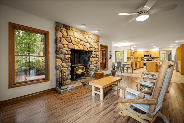 living room featuring ceiling fan, a wood stove, baseboards, recessed lighting, and light wood-style flooring
