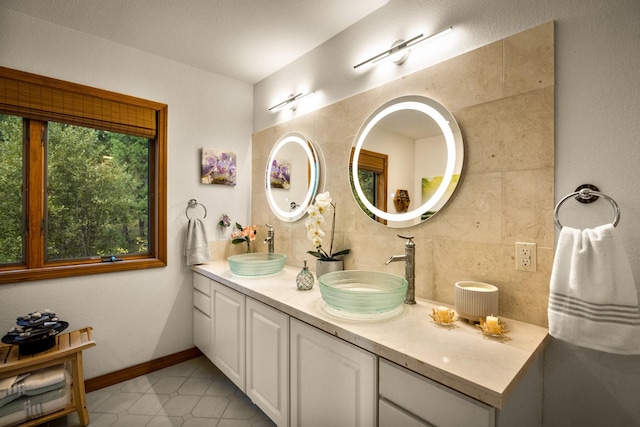 bathroom with double vanity, baseboards, a sink, and tile patterned floors