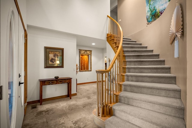 staircase with baseboards, recessed lighting, a towering ceiling, and visible vents