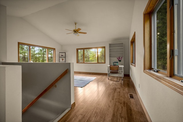 hallway featuring baseboards, an upstairs landing, wood finished floors, lofted ceiling, and visible vents