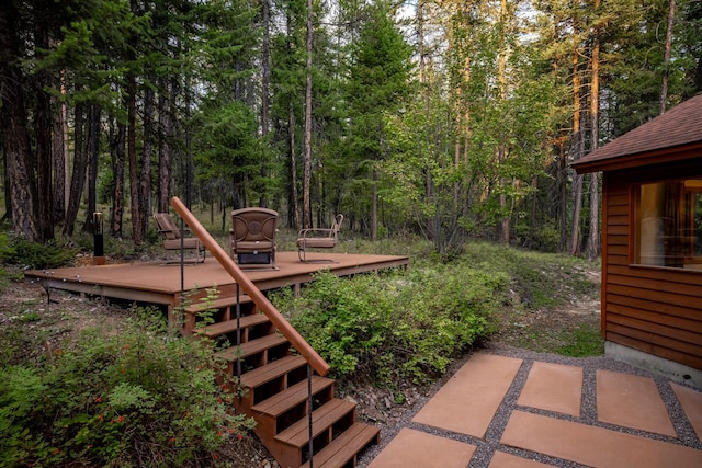 view of yard featuring a wooden deck, stairs, and a wooded view