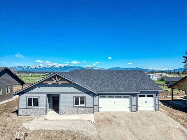 37 Hodgson Ct, Columbia Falls, MT 59912 - view of front of home featuring stone siding, a garage, driveway, and a mountain view