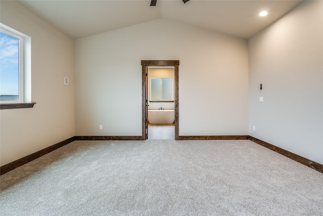 carpeted empty room featuring baseboards and lofted ceiling