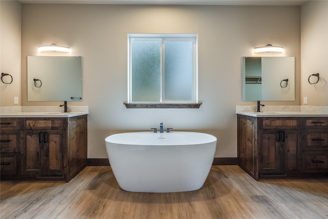 full bathroom with baseboards, wood finished floors, and two vanities