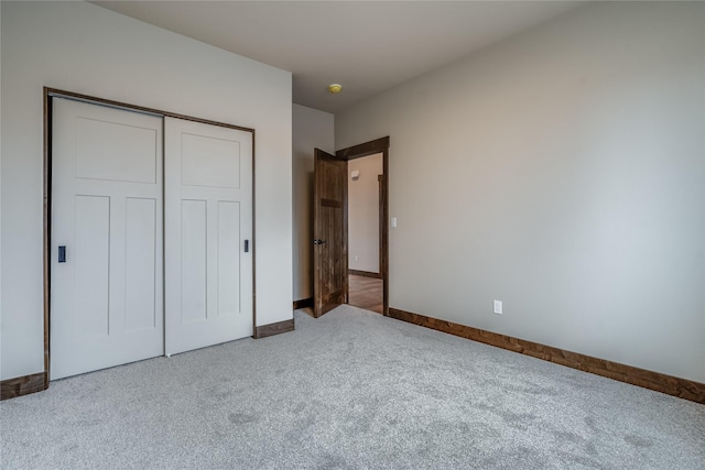 unfurnished bedroom featuring carpet floors, baseboards, and a closet