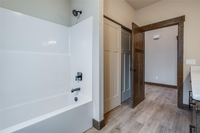 full bath with baseboards, wood finished floors, and bathing tub / shower combination