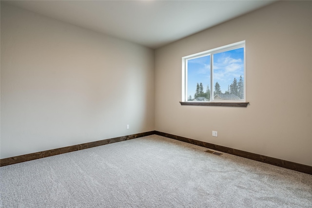 spare room with carpet flooring, baseboards, and visible vents