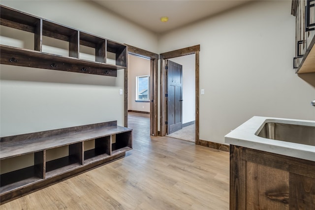 mudroom with baseboards, a sink, and light wood-style flooring
