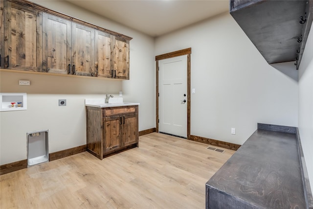 washroom with light wood-style floors, hookup for a washing machine, electric dryer hookup, and cabinet space