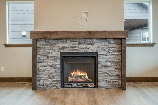 interior details with baseboards, wood finished floors, and a stone fireplace