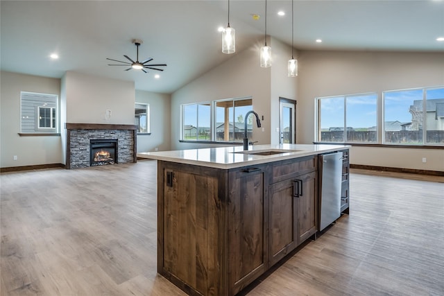 kitchen featuring dark brown cabinetry, ceiling fan, a sink, a kitchen island with sink, and baseboards