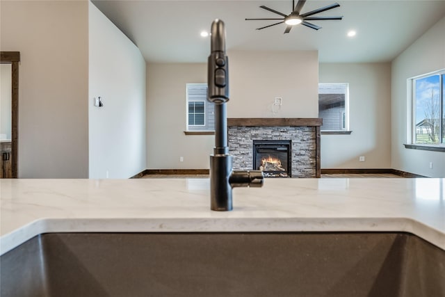 unfurnished living room featuring a stone fireplace, a ceiling fan, and recessed lighting