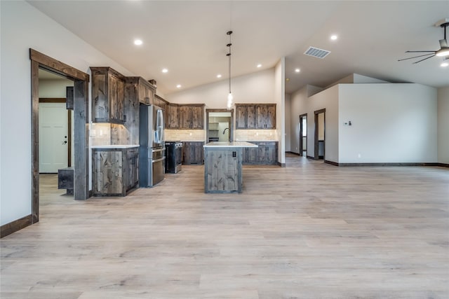 kitchen with visible vents, open floor plan, stainless steel fridge, and light countertops