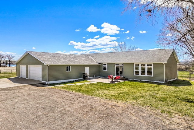 back of house featuring a lawn, an attached garage, driveway, and a patio