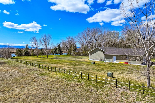 view of yard with fence and a rural view