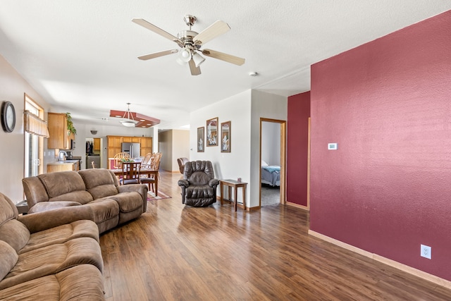 living room featuring baseboards, ceiling fan, and wood finished floors