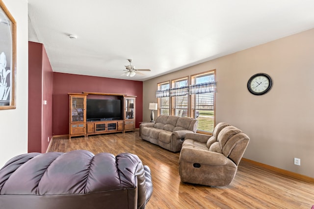 living room with a ceiling fan, baseboards, and wood finished floors