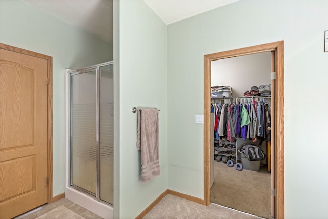 full bathroom with baseboards, a shower stall, and a spacious closet