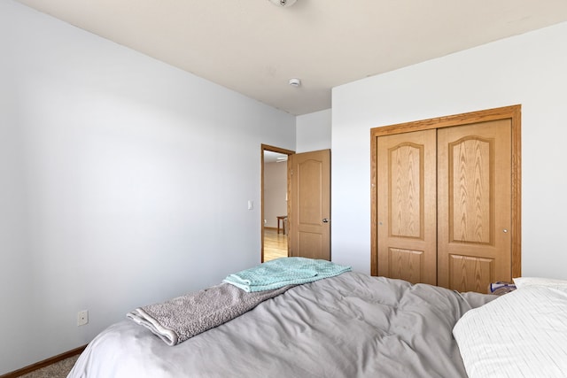 bedroom with carpet floors, baseboards, and a closet