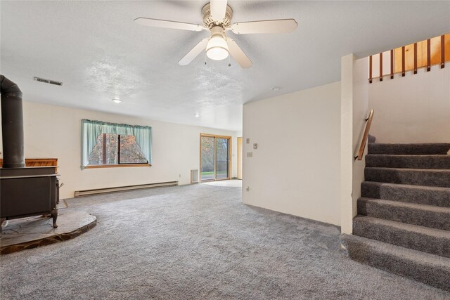 535 Reservoir Rd, Whitefish, MT 59937 - unfurnished living room featuring visible vents, baseboard heating, a wood stove, stairway, and carpet