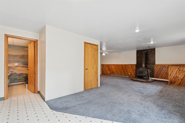 535 Reservoir Rd, Whitefish, MT 59937 - interior space featuring a wood stove, a wainscoted wall, a baseboard radiator, tile patterned floors, and wooden walls