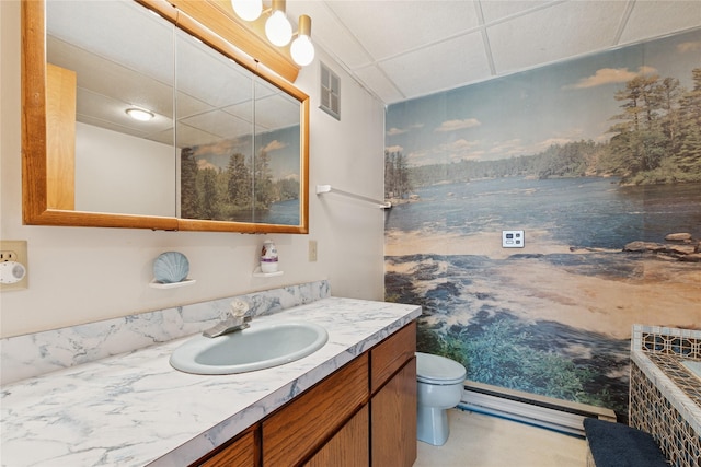 bathroom featuring visible vents, vanity, toilet, baseboard heating, and a paneled ceiling