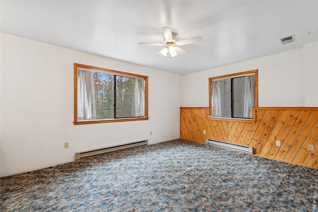 spare room with carpet flooring, a ceiling fan, visible vents, and a baseboard radiator