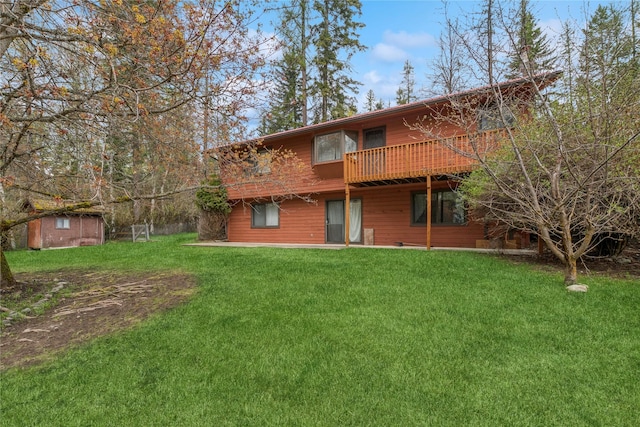 back of house with a lawn, a deck, an outdoor structure, and a storage unit