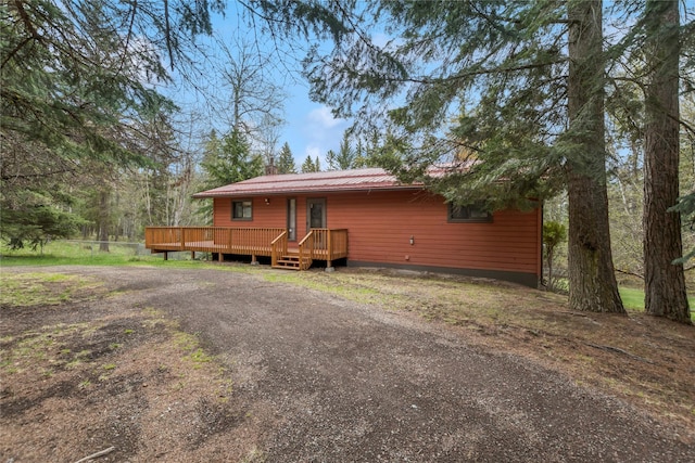 view of front of house with a chimney, a deck, and metal roof