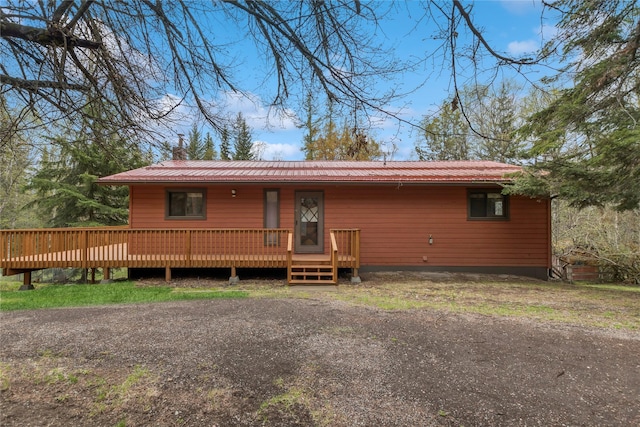 view of front of home featuring a wooden deck, a chimney, and metal roof