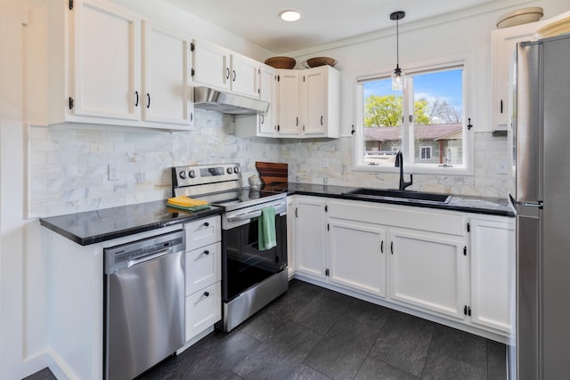 kitchen featuring a sink, appliances with stainless steel finishes, under cabinet range hood, and dark countertops