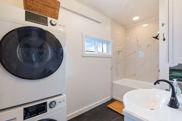 bathroom featuring stacked washing maching and dryer, baseboards, recessed lighting, and a sink