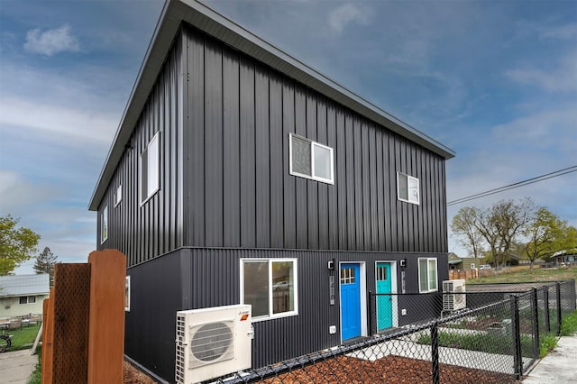 view of property exterior with board and batten siding, fence, and ac unit
