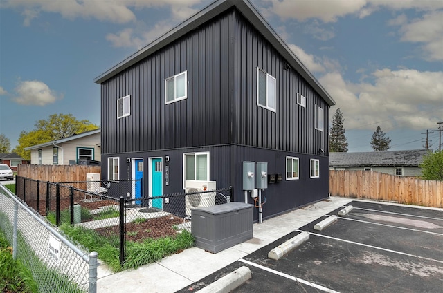 back of property featuring a fenced backyard, board and batten siding, a patio area, and uncovered parking