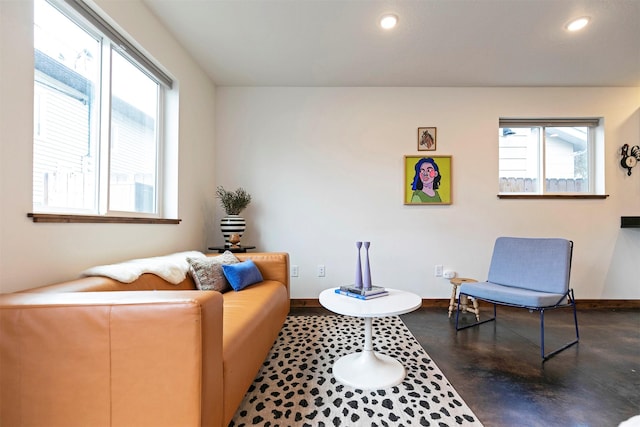 living area featuring finished concrete floors, recessed lighting, baseboards, and a healthy amount of sunlight