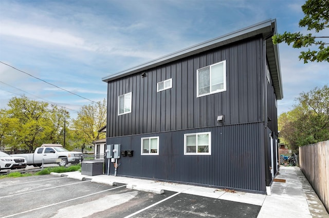 view of side of property featuring uncovered parking and fence