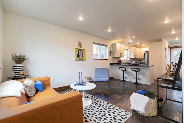 living room with baseboards, concrete flooring, and recessed lighting