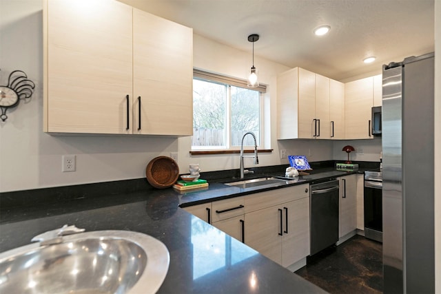 kitchen with recessed lighting, dark countertops, appliances with stainless steel finishes, and a sink
