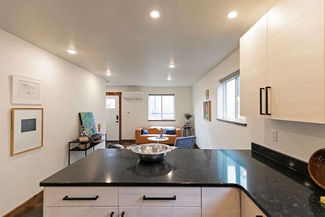 kitchen with a peninsula, baseboards, recessed lighting, white cabinetry, and a wall mounted AC