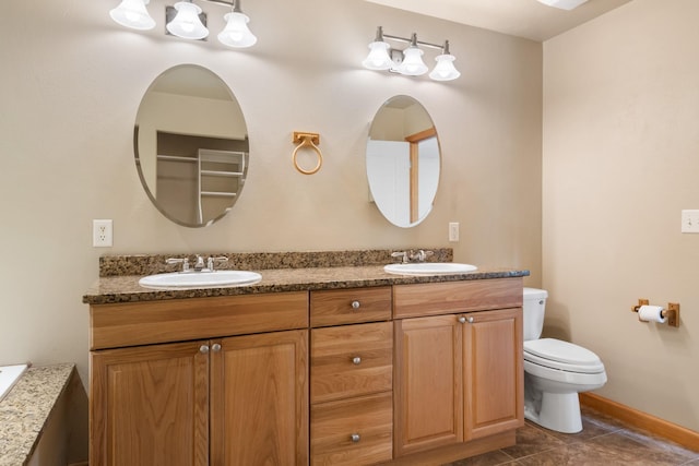 bathroom featuring double vanity, toilet, tile patterned floors, and a sink