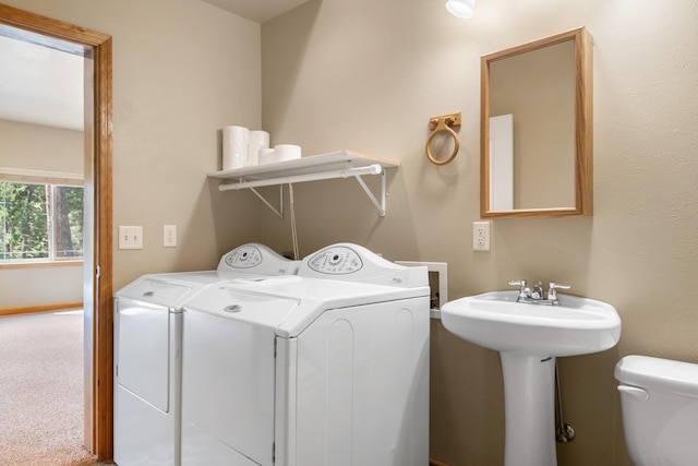 washroom with a sink, separate washer and dryer, and carpet