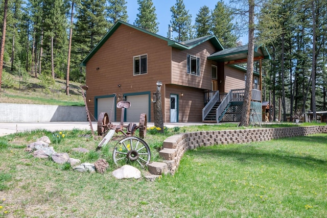 back of house featuring an attached garage, a yard, and stairway