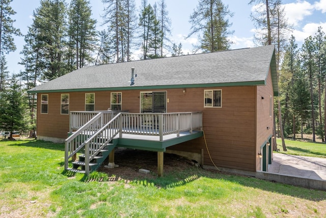 rear view of property with a lawn, a shingled roof, and a wooden deck