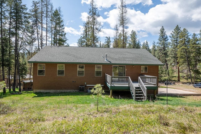 back of house with a lawn, a wooden deck, a shingled roof, and central air condition unit