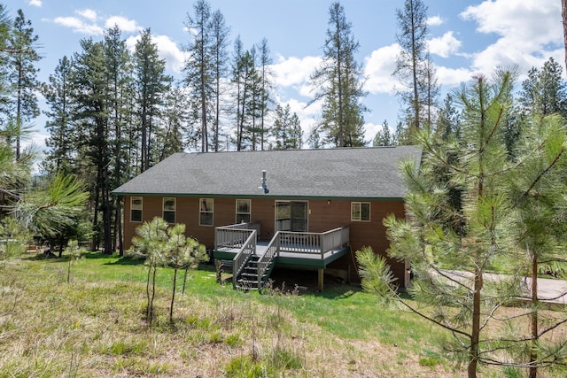 rear view of property featuring roof with shingles and a deck