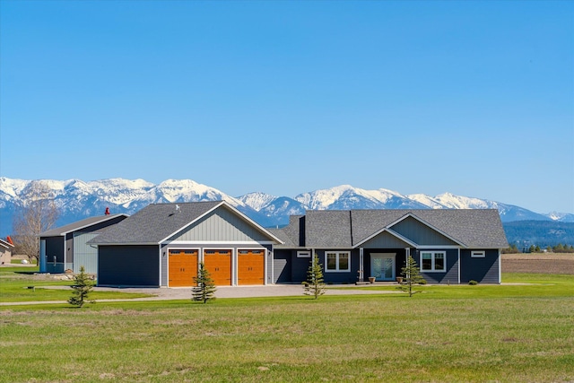 view of front facade with a front lawn, a garage, board and batten siding, a mountain view, and driveway