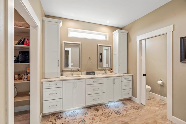 full bathroom featuring a sink, a walk in closet, toilet, and double vanity