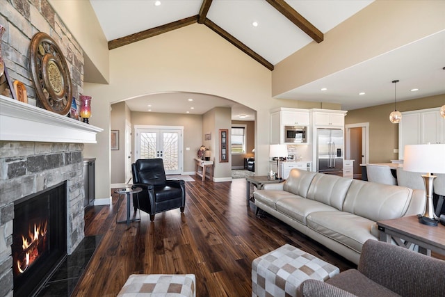 living area with arched walkways, high vaulted ceiling, dark wood finished floors, a stone fireplace, and baseboards