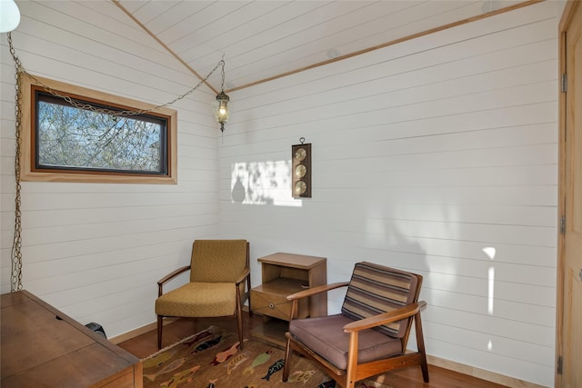 living area with wooden walls, wood ceiling, wood finished floors, and lofted ceiling
